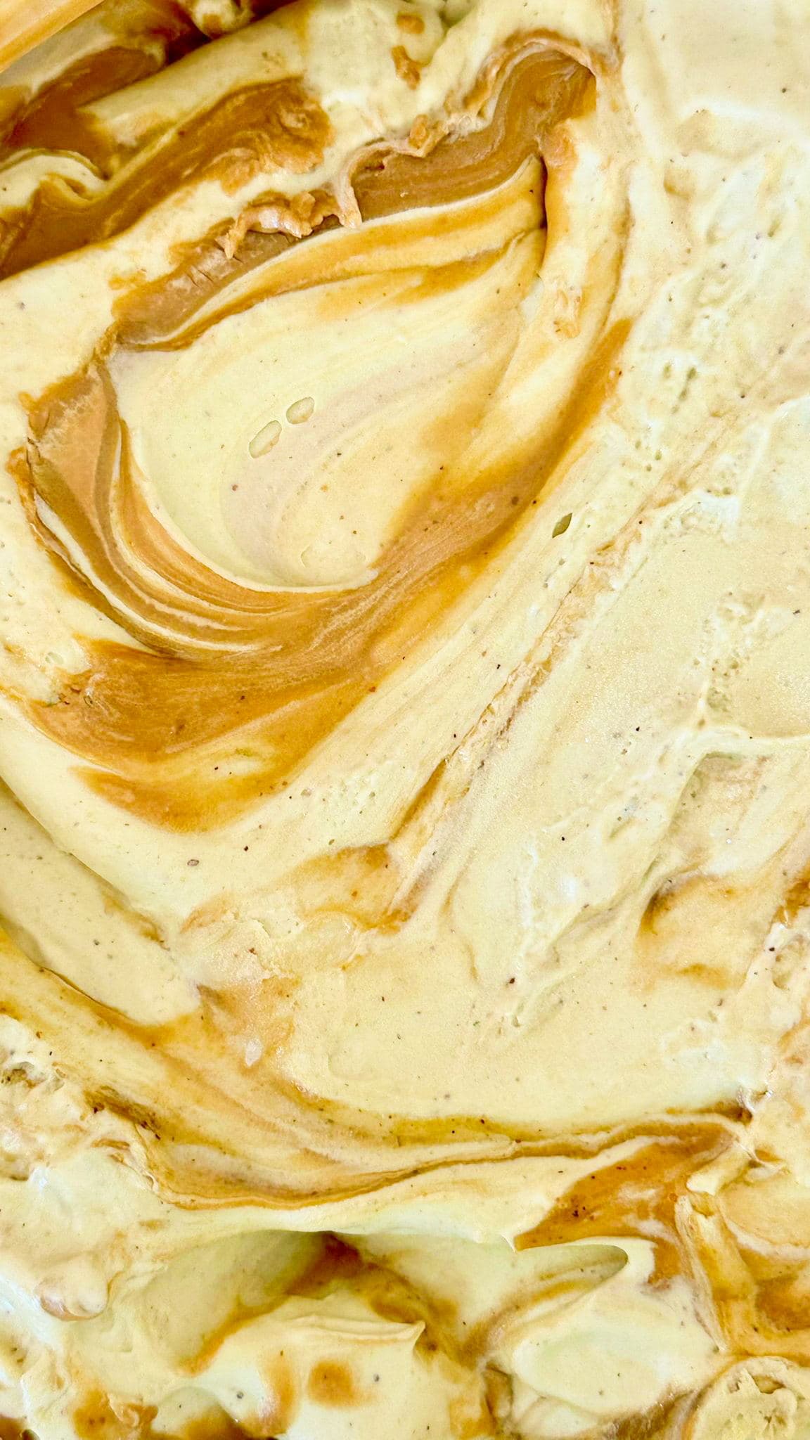 Freshly made gelato in a tray, with a caramel swirl folded through it