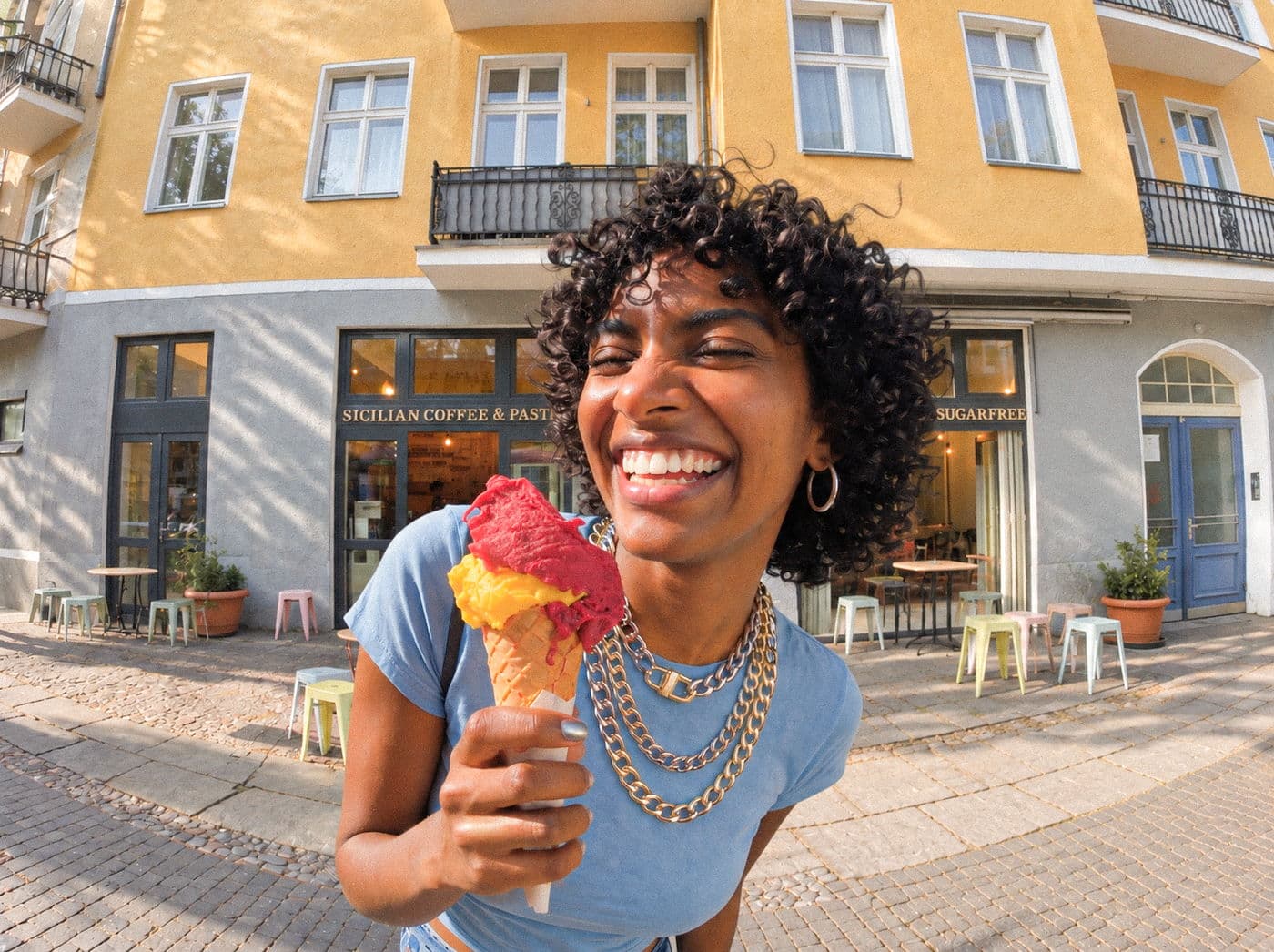 A gelato cone held up in front of a Duo shop front on a sunny street